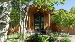 A wooden house with a large front door, stone steps, and a garden with various plants. - Luxurious Sun Valley Mountain Retreat on Golf Course (Sun Valley)