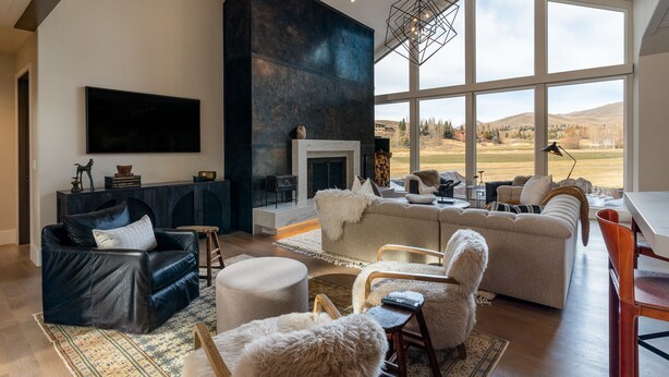 A spacious living room with a fireplace, large windows, and a high ceiling. - Luxurious Sun Valley Mountain Retreat on Golf Course (Sun Valley)