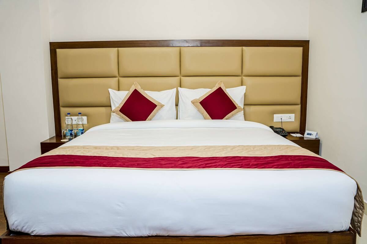 Une chambre d’hôtel avec un grand lit, deux tables de chevet, une tête de lit en bois et un plaid rouge.