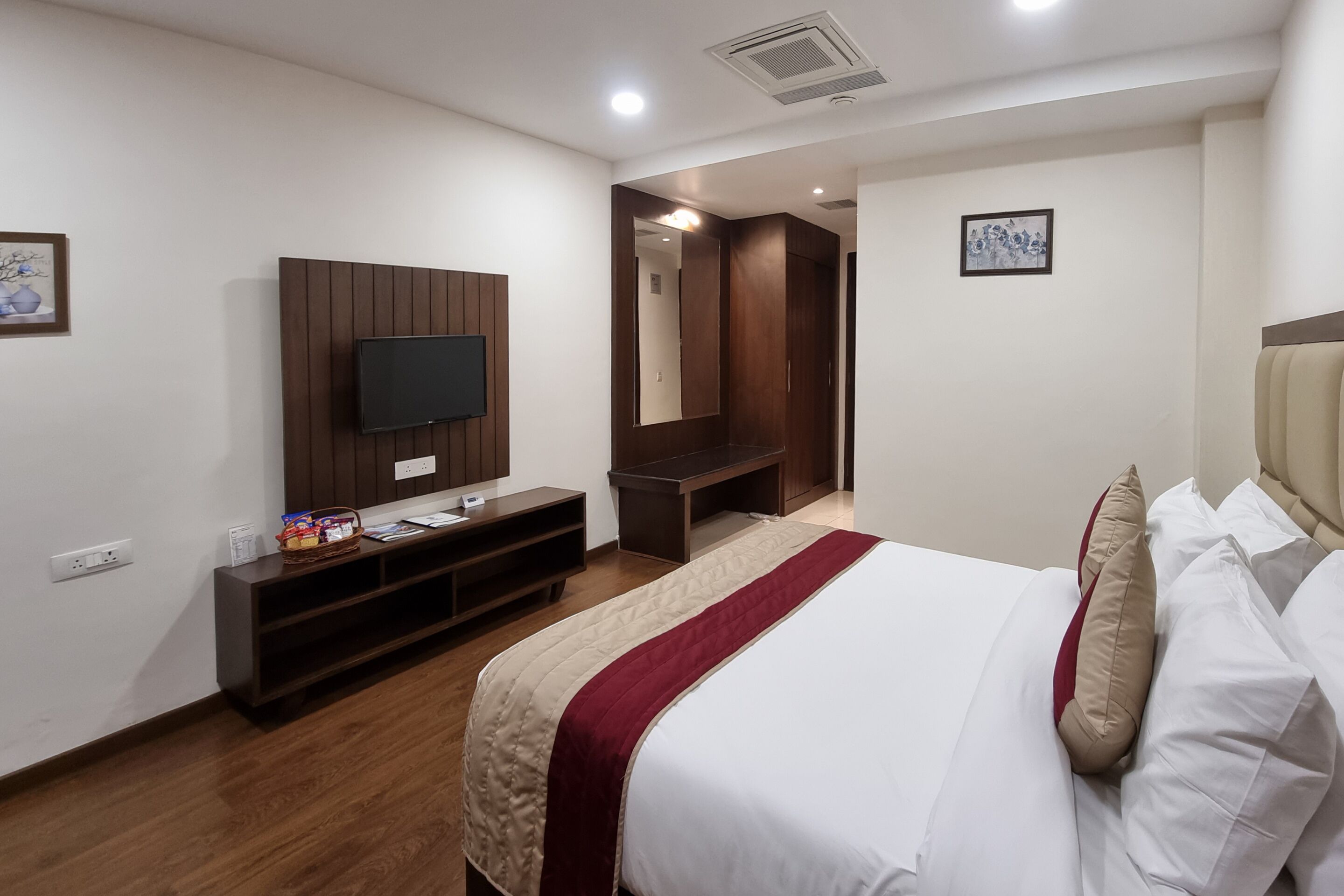 Une chambre d’hôtel équipée d’un lit, d’un téléviseur fixé au mur, d’un bureau et d’un miroir.