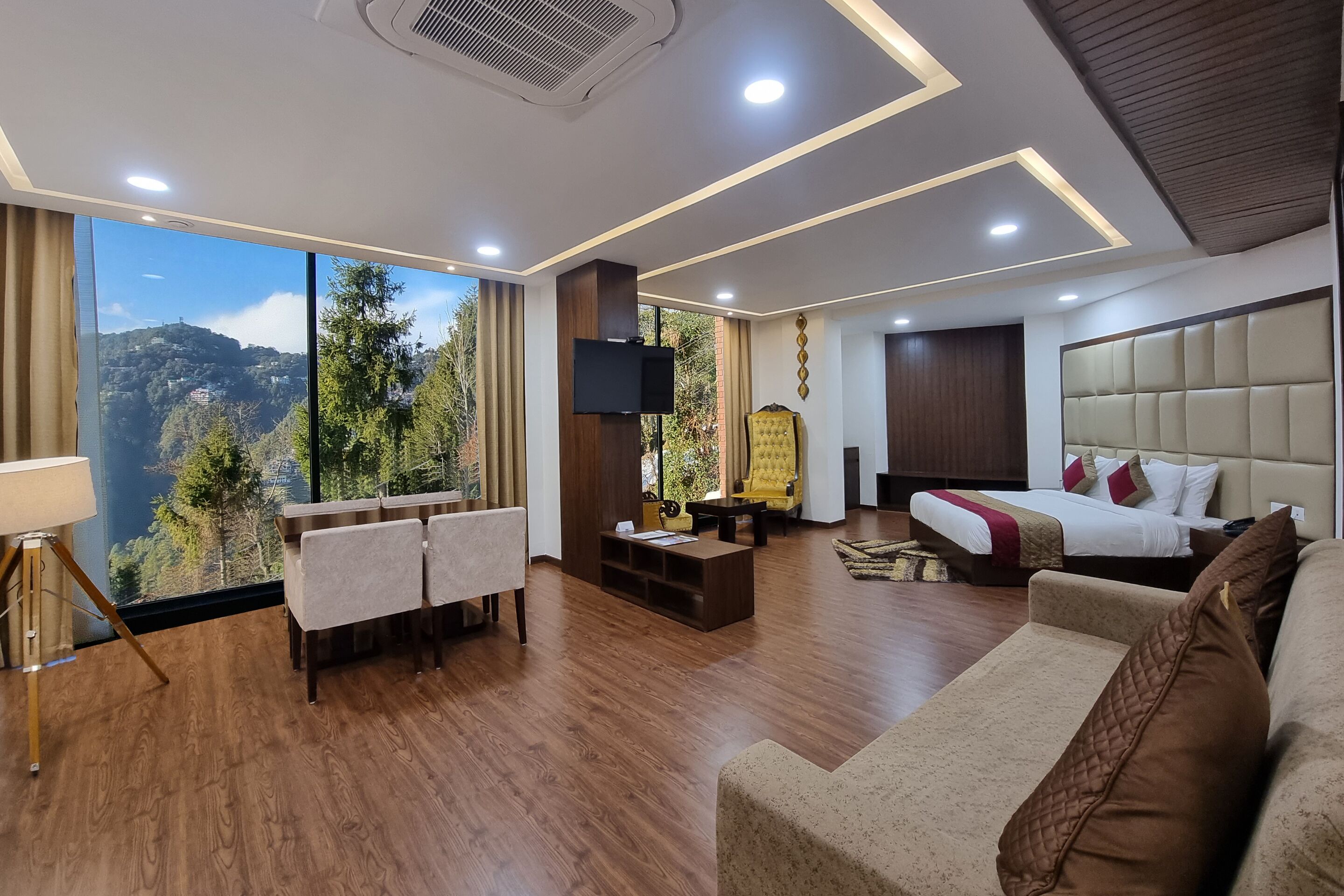 Una habitación de hotel moderna con un ventanal grande que ofrece vistas panorámicas, un sofá, una cama y un televisor.