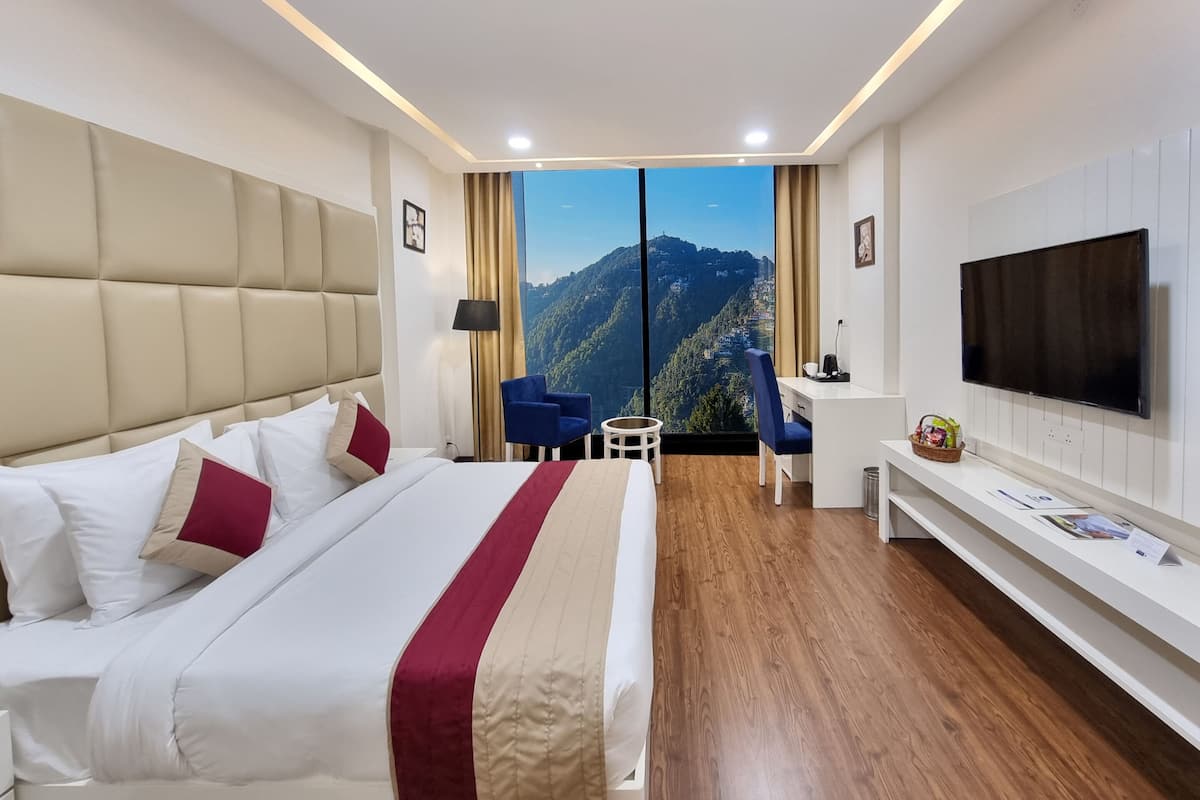 Une chambre d’hôtel moderne dotée d’un grand lit, d’un bureau, d’une télévision et d’un balcon offrant une vue sur la montagne.