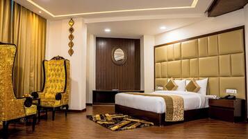 A hotel room with a large bed, a golden armchair, a wooden headboard, and a mirror on the wall.