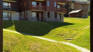 Un edificio de varios pisos con balcones, fachada de piedra y un patio cubierto de césped.