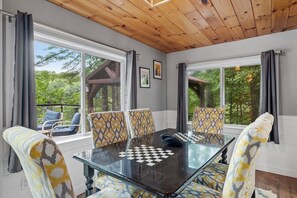 A room with a glass table and patterned chairs, large windows, and a wooden ceiling. - Lakefront Home-Stunning Views-Hot Tub, 3100 sqft! (Wakefield)