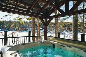 A hot tub with a view of a snowy landscape and trees.