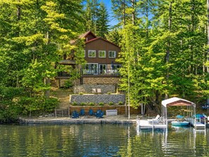 A lakeside cabin with a dock, outdoor seating, and a covered area.
