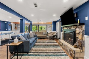 A modern living room with a fireplace, a sofa, a chair, and a television mounted on the wall.
