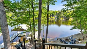 A deck with a view of a calm lake, surrounded by trees and docked boats. - Lakefront Home-Stunning Views-Hot Tub, 3100 sqft! (Wakefield)