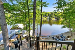 A deck with a view of a calm lake, surrounded by trees and docked boats. - Lakefront Home-Stunning Views-Hot Tub, 3100 sqft! (Wakefield)