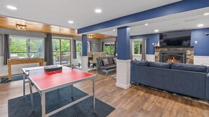 A modern living room with a ping pong table, a fireplace, and a comfortable seating area. - Lakefront Home-Stunning Views-Hot Tub, 3100 sqft! (Wakefield)