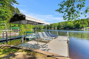 A dock with lounge chairs, a covered seating area, and a boat ramp.
