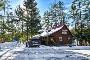 A cabin with a sloped roof, surrounded by snow and tall trees. - Lakefront Home-Stunning Views-Hot Tub, 3100 sqft! (Wakefield)