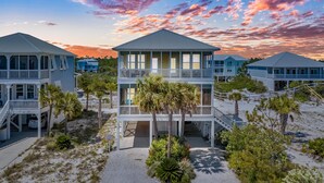 A beachfront property with multiple-story buildings, a covered walkway, and palm trees.