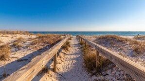 A wooden boardwalk leading to a beach with clear skies.