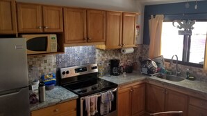A kitchen with wooden cabinets, a microwave, a stove, and a sink. - 2 Bed 2 Bath condo with pool, full kitchen, in the marine sunset condos. (Playa del coco)
