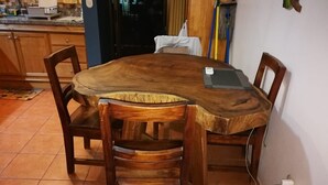 A wooden dining table with four chairs, a laptop on the table, and a power outlet on the wall. - 2 Bed 2 Bath condo with pool, full kitchen, in the marine sunset condos. (Playa del coco)