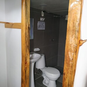 Bathroom features a pedestal sink and toilet, with a tiled wall.