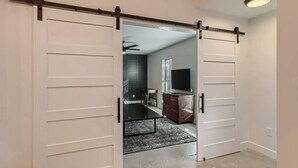 A room with a sliding door, a flat-screen TV, a wooden dresser, and a ceiling fan. - Family Relaxation: Private Pool & Spa with Games (Austin)