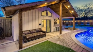 A covered outdoor area with a pool, a wooden deck, and a leather sofa. - Family Relaxation: Private Pool & Spa with Games (Austin)
