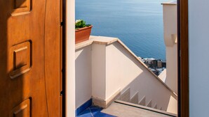 Une porte en bois donnant sur un balcon avec vue sur la mer.