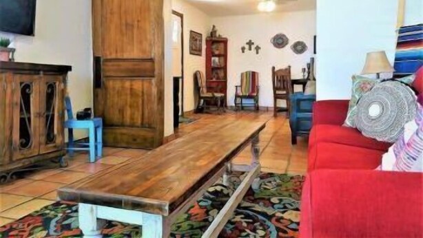 A living room with a wooden bench, a red sofa, and a patterned rug.