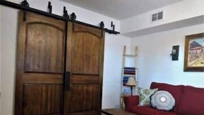 A room with a wooden wardrobe, a red sofa, and a patterned rug.