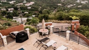 Area piscina sul tetto con sedie a sdraio e barbecue.