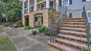 Een twee verdiepingen tellend huis met een stenen veranda en een overdekte veranda, met een trap naar de bovenverdieping.