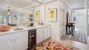 Una cocina moderna con muebles blancos, lavavajillas de acero inoxidable y una alfombra colorida.