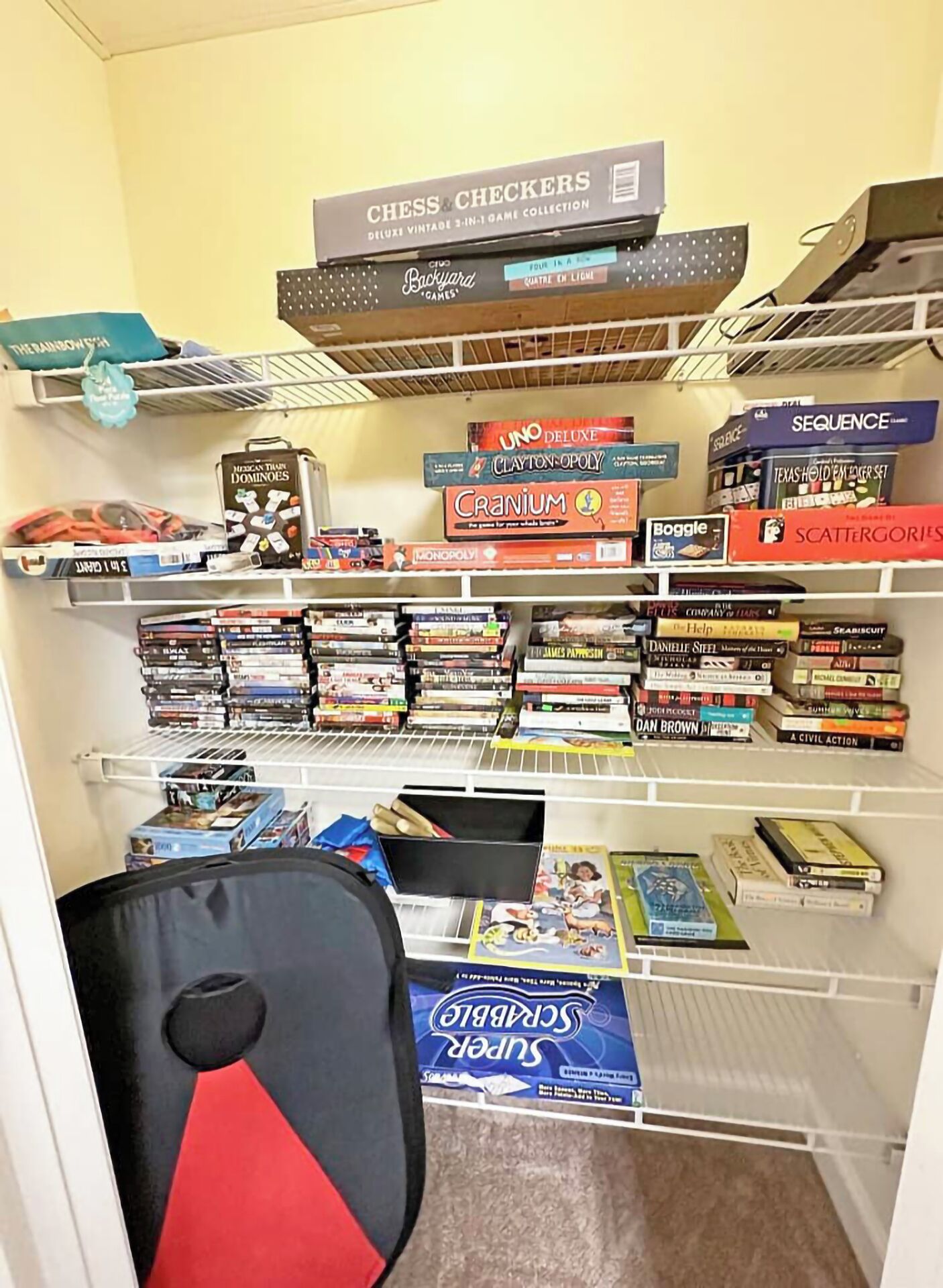 A game room with shelves stocked with board games, a chair, and a small table.