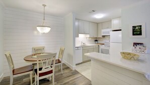 Eine moderne Küche mit weißen Schränken, ein Essbereich mit einem Holztisch und Stühlen sowie eine Chandelier.