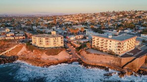 A coastal urban area with buildings, a rocky shoreline, and waves.