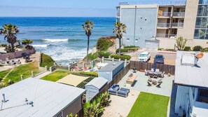 A coastal building with a rooftop patio, a pool, and a view of the ocean.