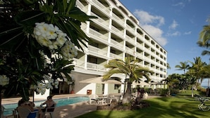 Un hotel con piscina, palmeras y vista al océano.