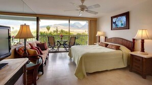 Habitación de hotel con balcón, cama, sofá, televisión y mesa.