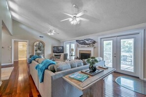 Relax in this inviting living room with a large sofa, coffee table, and fireplace, leading to an outdoor deck.