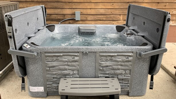 A spa tub with a stone exterior, a control panel, and a small table in front. - Cedar Mountain Lodge (Bryant)