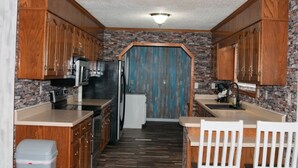 A kitchen with wooden cabinets, a refrigerator, a microwave, and a sink. - Cedar Mountain Lodge (Bryant)