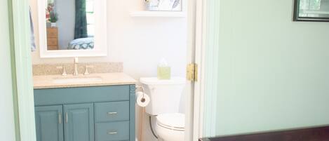 A bathroom with a toilet, sink, and cabinet.