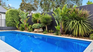 A swimming pool surrounded by tropical plants and a black wall. - KAMALA - MOUNT ELIZA (Mount Eliza)