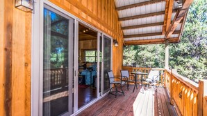 A wooden deck with a covered area, sliding glass doors leading to an interior space, and outdoor seating.