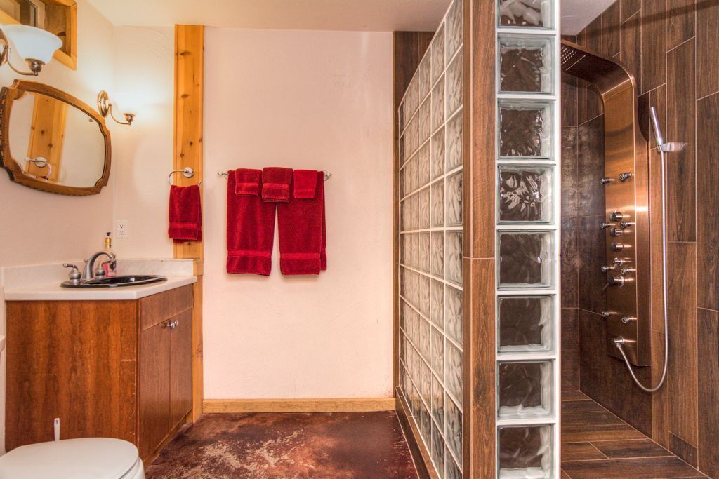 A bathroom with a wooden vanity, a white toilet, and a glass shower enclosure.