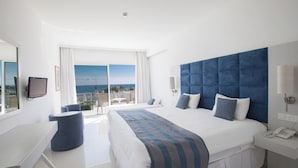 Habitación de hotel moderna con una cama grande, un escritorio, una silla, un televisor y un balcón con vistas.