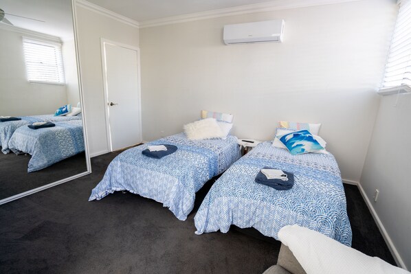 A room with two beds, a mirror, and an air conditioning unit.