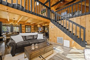 Ein Holzinnenraum mit Treppe, einem Ledersofa, einem Holztisch und einer Küchenzeile.