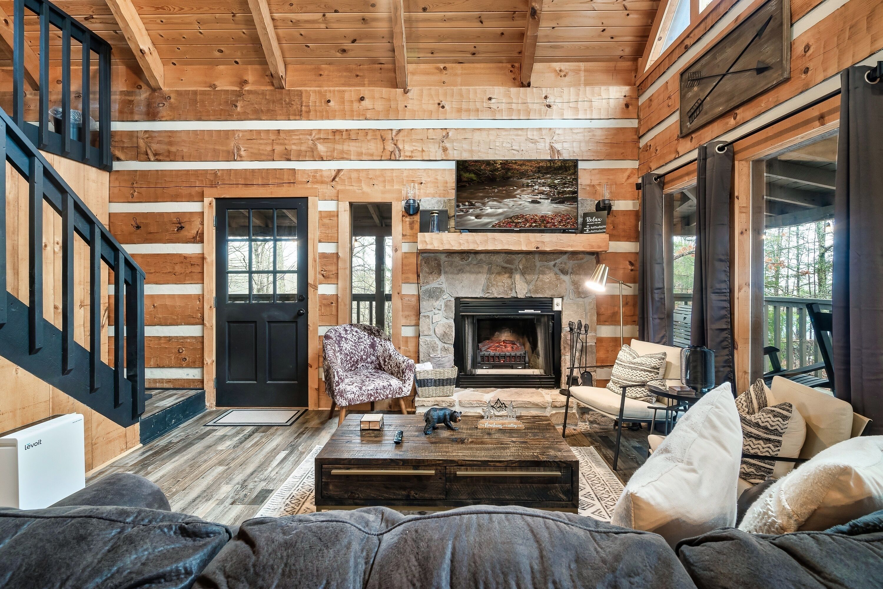 L’intérieur d’une cabane en rondins, avec une cheminée, un canapé, une table basse et un téléviseur.