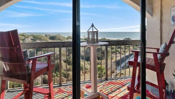 A balcony with a view of the ocean, a lantern, and red chairs. - OCEAN VIEW- PETS ALLOWED! (Myrtle Beach)