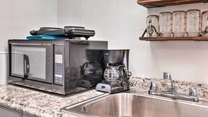 Une cuisine équipée d’un four à micro-ondes, d’une machine à café et d’un évier en acier inoxydable.