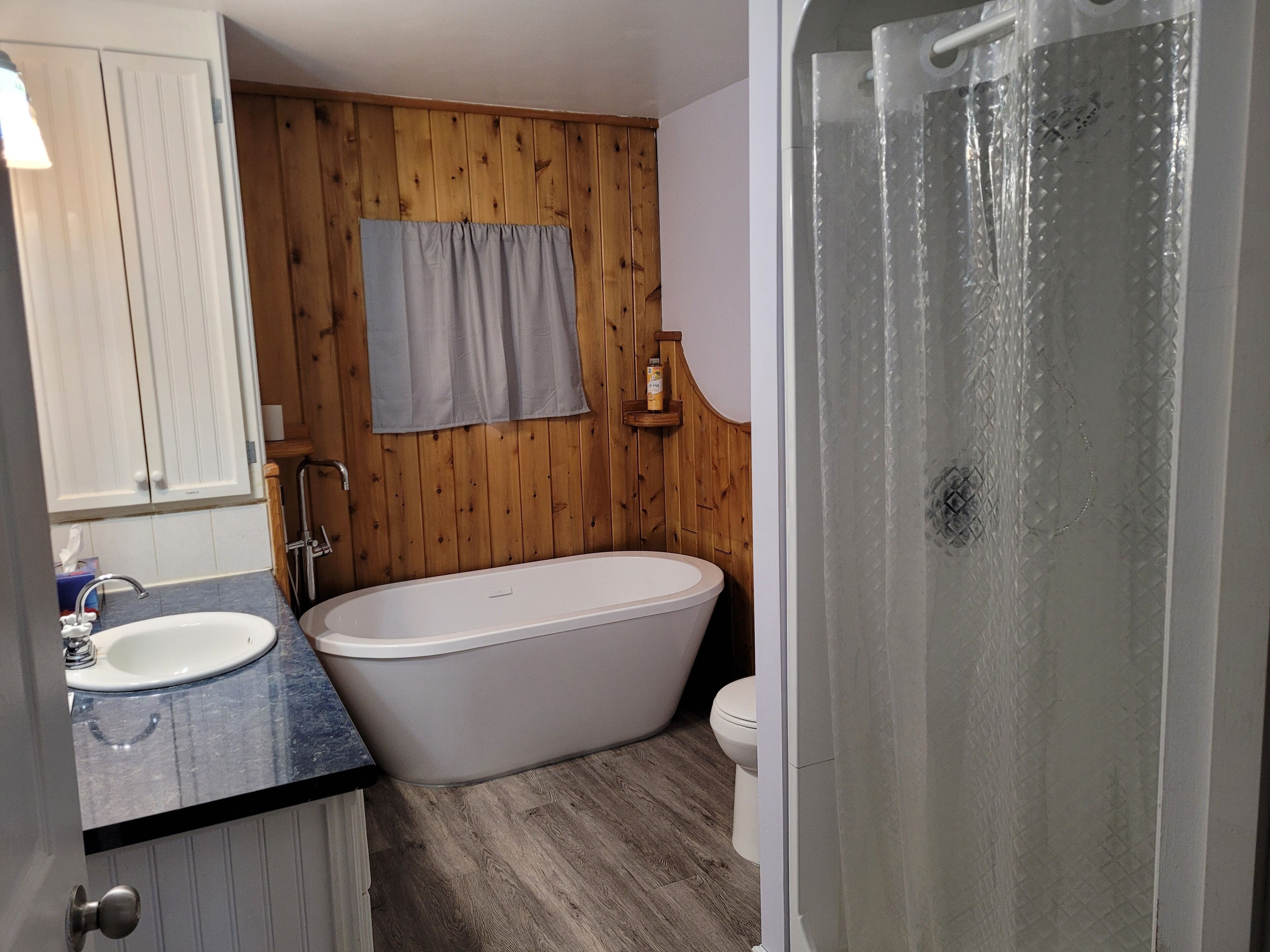 Une salle de bain avec un mur en bois, une baignoire, des toilettes et un lavabo.